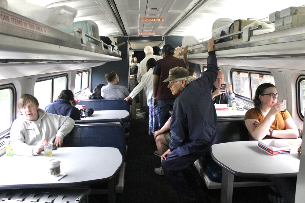 Line of people in aisle of passenger car with tables