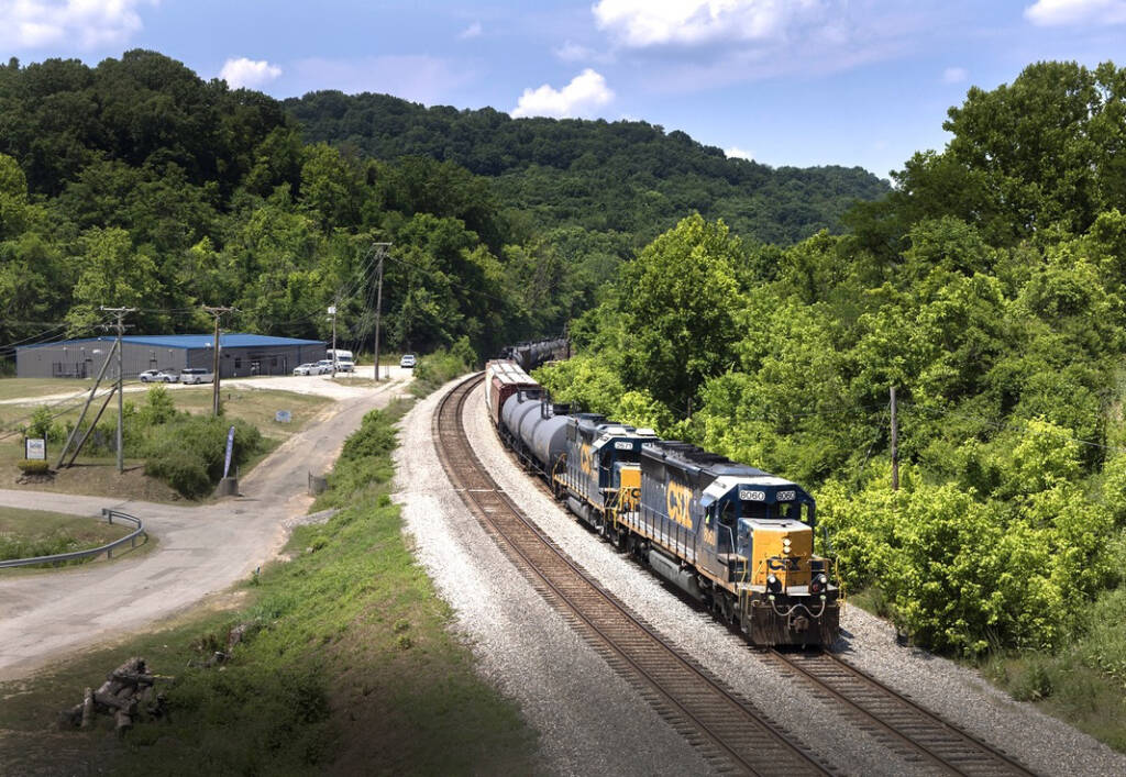 Freight train on curve, with front in sunlight but approaching shadows