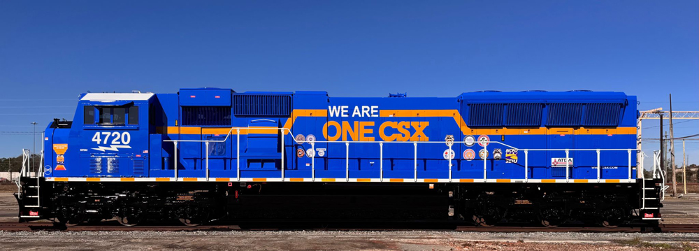 Side view of blue locomotive with yellow stripe and "One CSX" logo