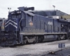 Dark blue diesel locomotive with red logo outside shop building