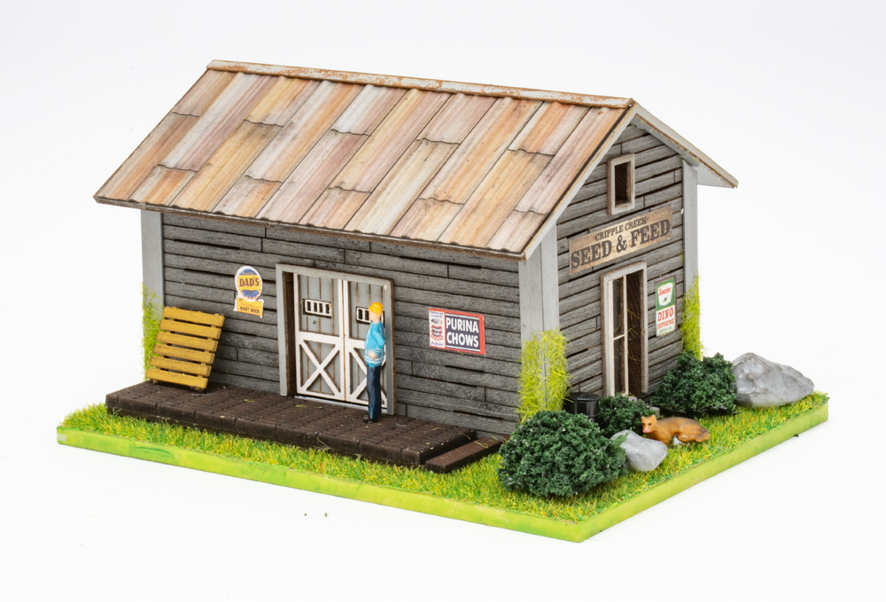 Color image of weathered gray HO scale building with scenicked base on white background.