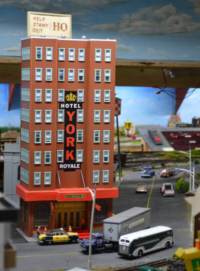 preserving the history of model railroading: A tall red brick building on a model railroad layout with a sign on top which reads "Stamp out HO"