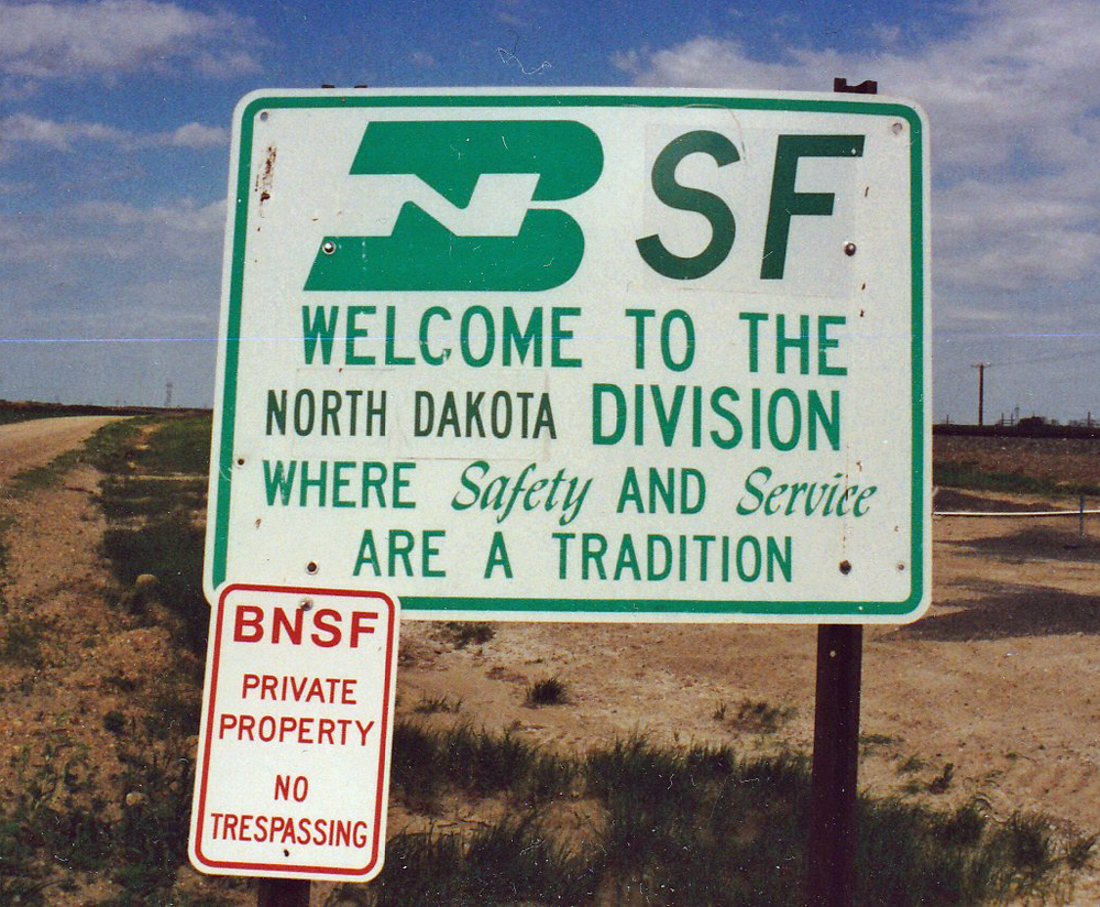 Color photo of green-and-white metal sign mounted on metal posts.