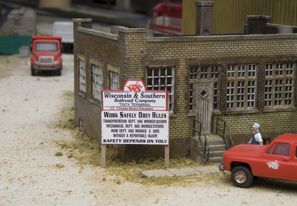 Color photo of sign next to brick building on a model railroad.