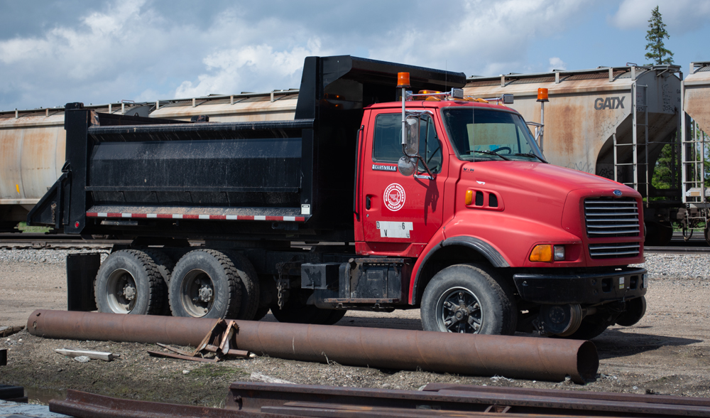 Color photo of dump truck with red cab and black body.