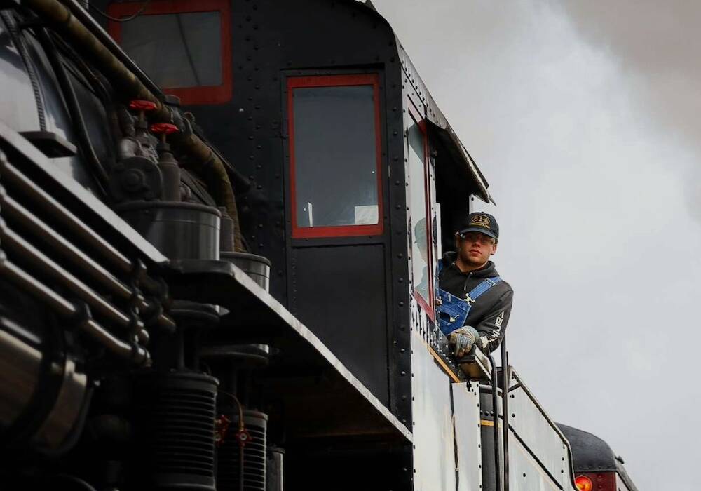 Young fireman leaning out of the cab of a steam locomotive