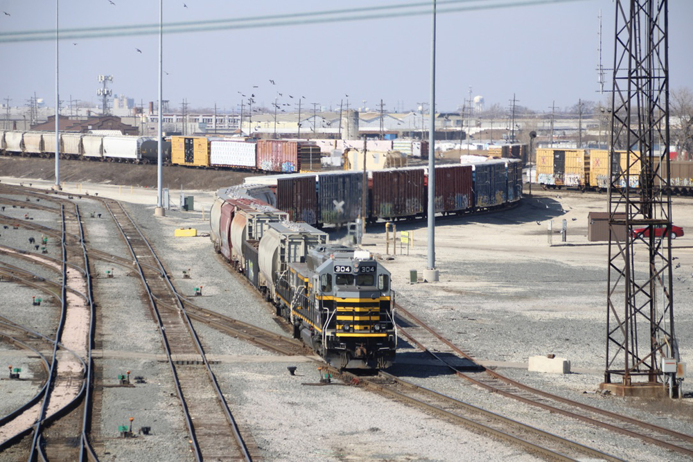 Black, gray and yellow locomotive and slug with string of freight cars