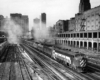 Streamlined diesel locomotive with passenger train in urban canyon