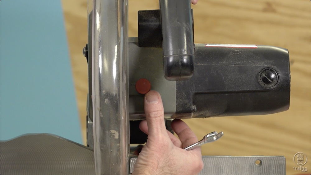 Finger point to red button on a circular saw.