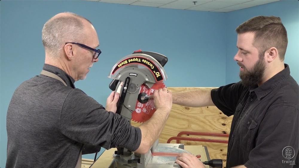 Two workers putting a new blade into the circular saw.