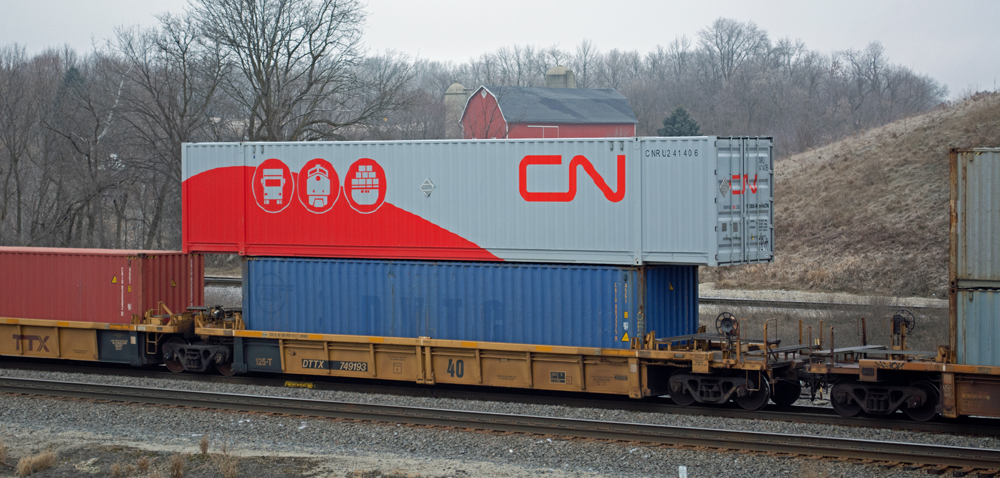 Color photo of yellow articulated well cars loaded with various intermodal containers.