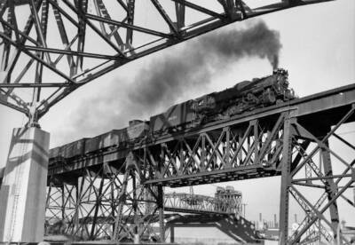 Steam locomotive pulling a freight train over a bridge.