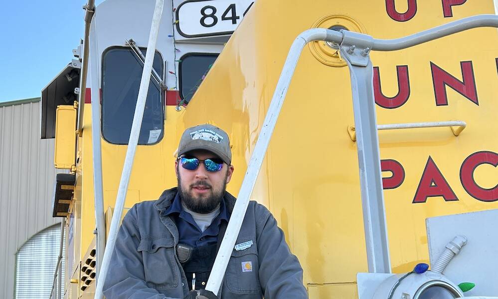 Young individual standing in front of a yellow diesel.