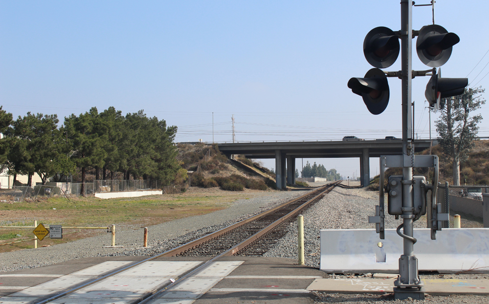 Railroad grade crossing with highway bridge in background