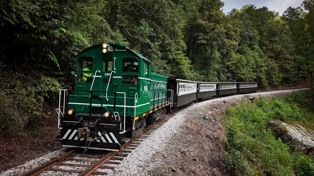 Green end-cab switcher with four passenger cars