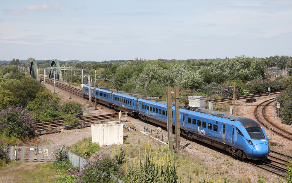 Five-car solid blue EMU passenger train at diamond