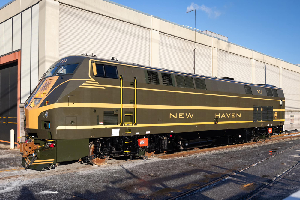 Outdoor side view of green and yellow locomotive