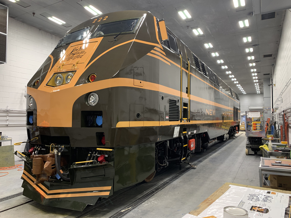 Olive green and yellow locomotive in shop building