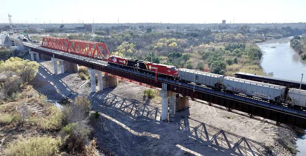 Train with two CPKC locomotives crossing bridge