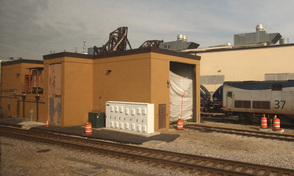 Gold-colored building with railroad track leading into opening at one end