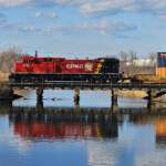 Single locomotive in CPKC paint scheme crossing bridge