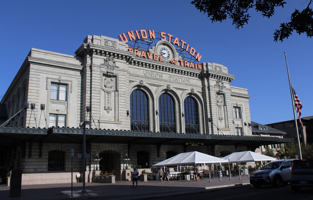 Front of large passenger station with "Union Station — Travel by Train" sign at top