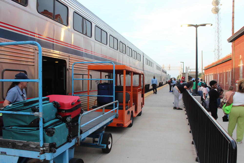 Baggage cart next to bilevel passenger train at station