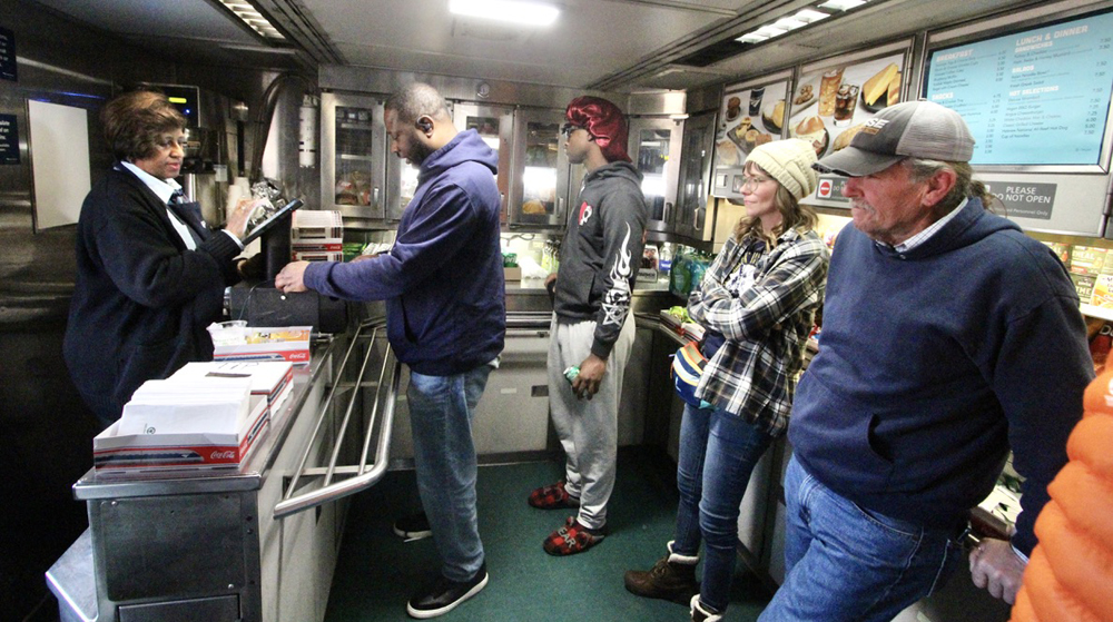 Woman waits on customers at counter in passenger car