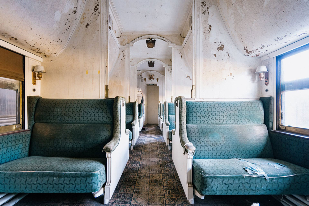 Interior of vintage passenger car showing damage and wear to paint and seats