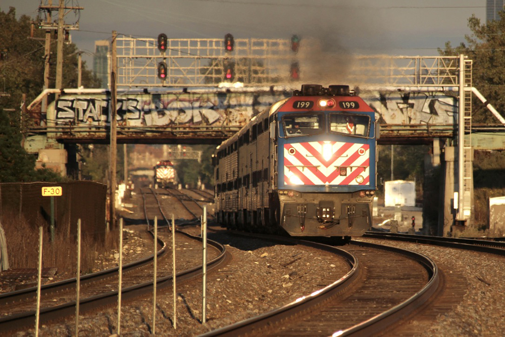 Two commuter trains on three-track main line in golden-hour lighting